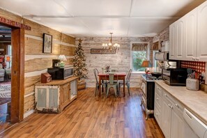 Una cocina rústica con paredes de madera, una mesa de comedor y un árbol de Navidad.