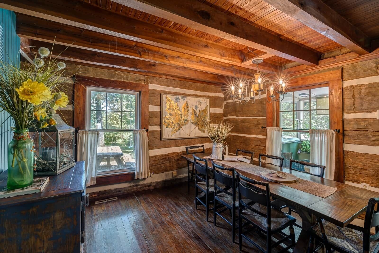 Ein rustikales Holzinterieur mit einem Esstisch, Stühlen und einer Chandelüster.
