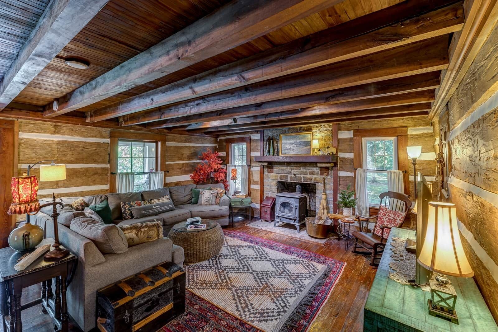 L’intérieur d’un chalet rustique, avec un plafond en bois, une cheminée, un canapé et une table à manger.