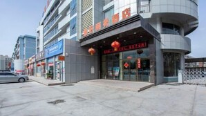 Un hotel con fachada moderna, entrada en esquina curva y faroles rojos colgando sobre la puerta.