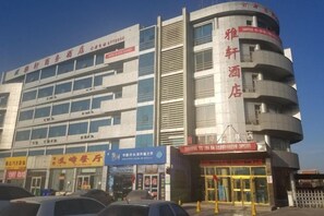 Un immeuble à plusieurs étages, avec des enseignes indiquant la présence d’un hôtel et d’autres commerces.