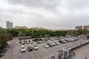 Un estacionamiento con varios automóviles y vistas de un paisaje urbano con edificios y árboles.