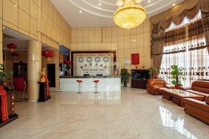 Vestíbulo de hotel con mostrador de recepción, zona de estar y elementos decorativos.