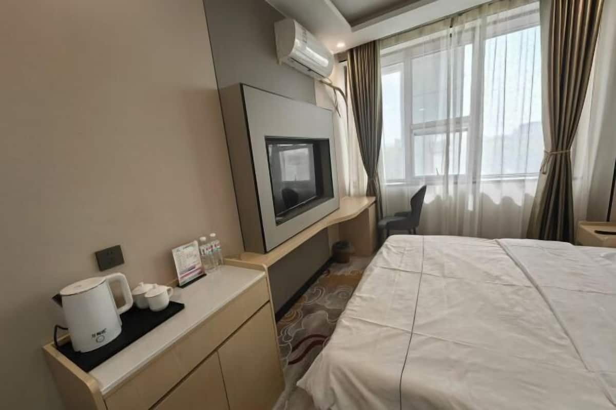 Une chambre d’hôtel équipée d’un lit, d’un téléviseur fixé au mur, d’une machine à café et d’une petite table avec des tasses et un menu.
