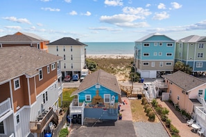 Une propriété située en bord de mer, comprenant plusieurs bâtiments, offrant une vue sur la plage et abritant une maison bleue où vit un chien.