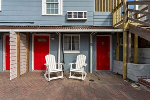 A building with two red doors, a window, and two rocking chairs in front.