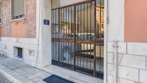 A building entrance with a metal gate, a small window with a towel hanging, and a sign indicating a family room. - Lovely Rooms by Rentbeat (Civitavecchia)