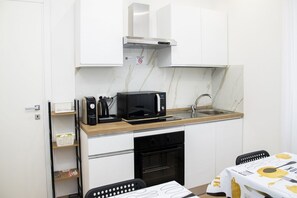 Eine kleine Küchenzeile mit Mikrowelle, Kaffeemaschine und Spüle.