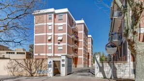 A multi-story residential building with a gated entrance, a parking area, and a clear sky. - Lovely Rooms - Room 3 by Rentbeat (Civitavecchia)