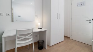 A white room with a desk, chair, wardrobe, and a door. - Lovely Rooms - Room 3 by Rentbeat (Civitavecchia)