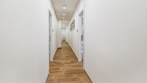A narrow hallway with white walls and wooden flooring, leading to a door at the end. - Lovely Rooms - Room 3 by Rentbeat (Civitavecchia)