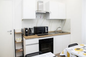 Een kleine keuken met een magnetron, koffiezetapparaat en een spoelbak.