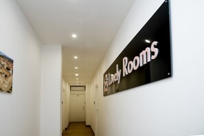 Un couloir avec une pancarte indiquant « Belles chambres » et une porte au bout.