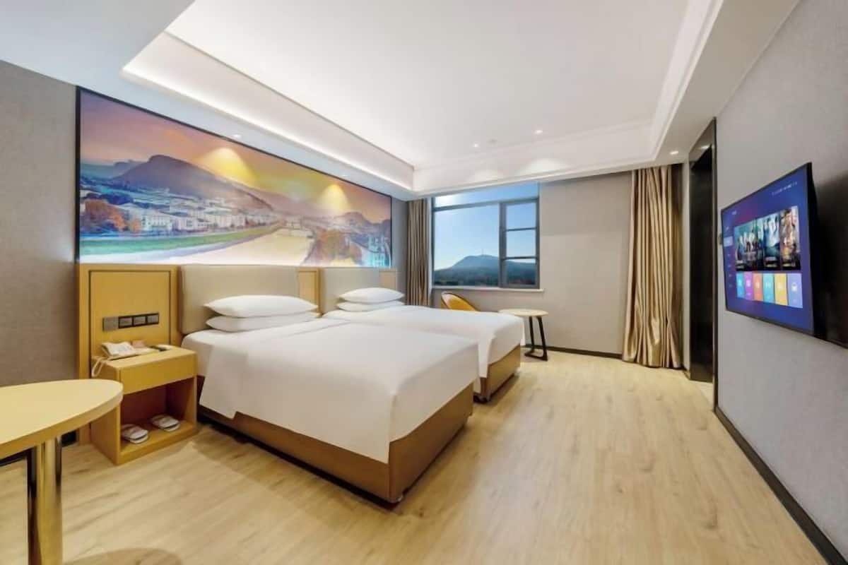 Habitación de hotel con una cama grande, una mesita de noche, un televisor y un cuadro en la pared.