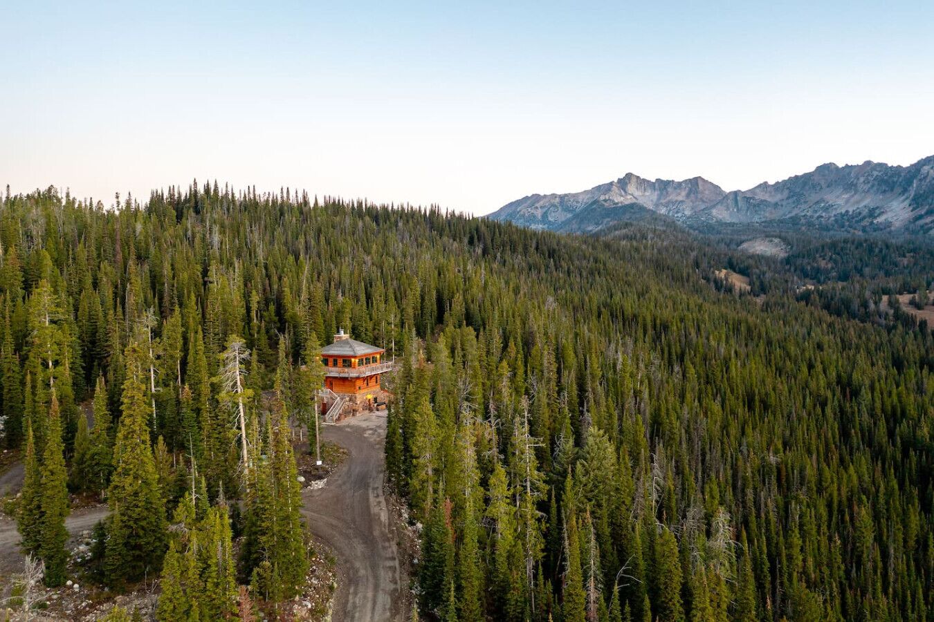 Un chalet situé dans une forêt, accessible par un chemin de terre.