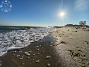 Ein Strand mit Wellen, Seetang und Fußspuren.