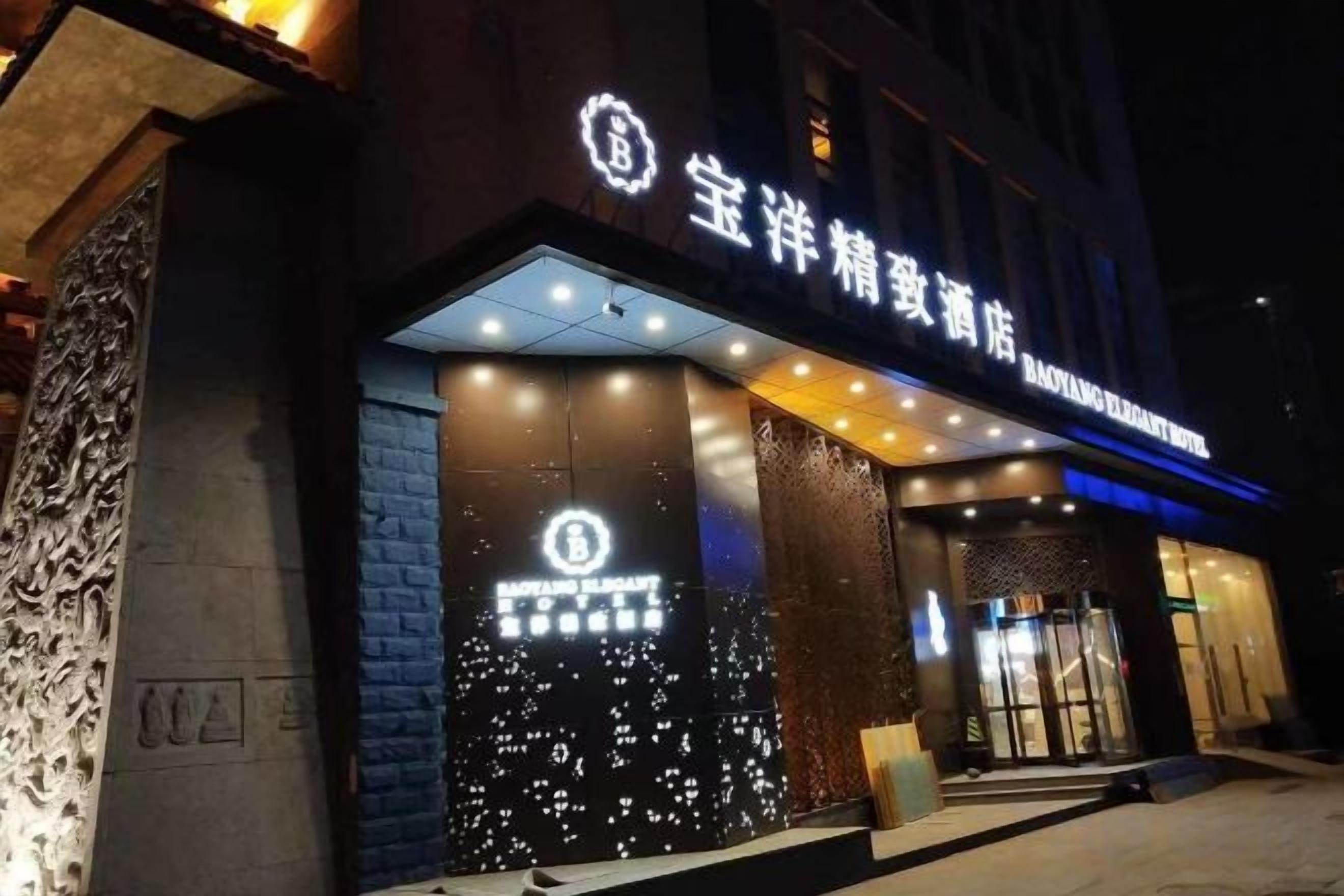 A hotel entrance with illuminated signage and a modern facade.