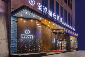 A hotel entrance with illuminated signage, a red carpet, and a modern facade. - Baoyang Boutique Hotel (Shijiazhuang North Zhonghua Street Zhongchu Plaza) (Shijiazhuang)