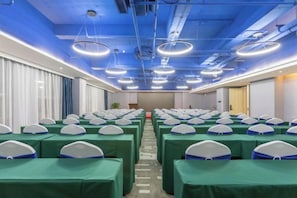 A conference room with rows of tables and chairs, a blue ceiling, and modern lighting fixtures. - Baoyang Boutique Hotel (Shijiazhuang North Zhonghua Street Zhongchu Plaza) (Shijiazhuang)