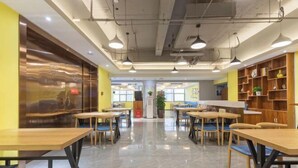 A spacious indoor area with multiple tables and chairs, a central pillar, and shelves with various items. - Baoyang Boutique Hotel (Shijiazhuang North Zhonghua Street Zhongchu Plaza) (Shijiazhuang)