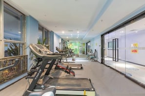 A gym with treadmills, exercise bikes, and a mirrored wall. - Baoyang Boutique Hotel (Shijiazhuang North Zhonghua Street Zhongchu Plaza) (Shijiazhuang)