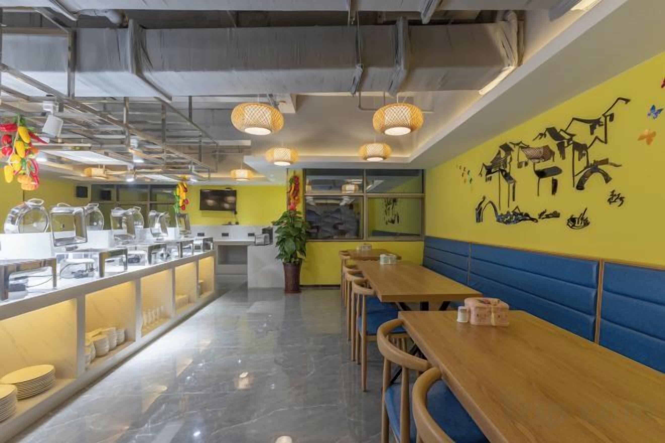 Una cafetería con mesas de madera largas y un mostrador de buffet.