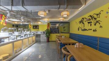 Una cafetería con mesas de madera largas y un mostrador de buffet.