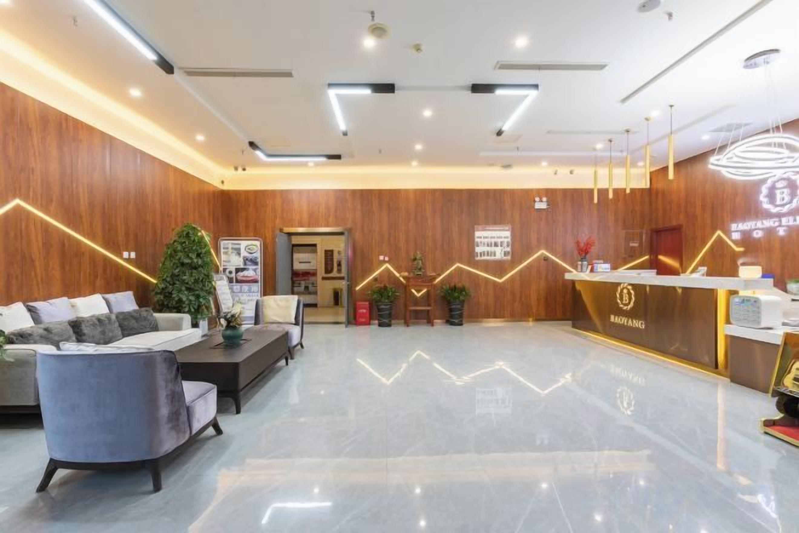 En hotellobby med reception, siddeområde og en trævæg.