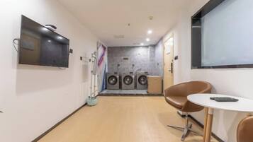 A laundry room with a washing machine, dryer, and a small table with chairs.