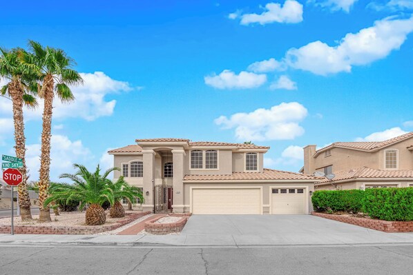 A two-story house with a garage, palm trees, and a stop sign.