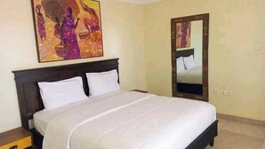 Une chambre à coucher avec un grand lit, une table de chevet, un tableau et un miroir.