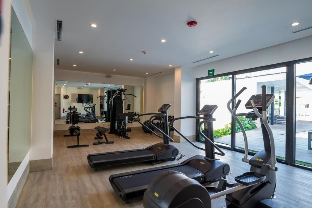 Une salle de sport moderne équipée de tapis de course, de vélos elliptiques et de matériel de musculation.