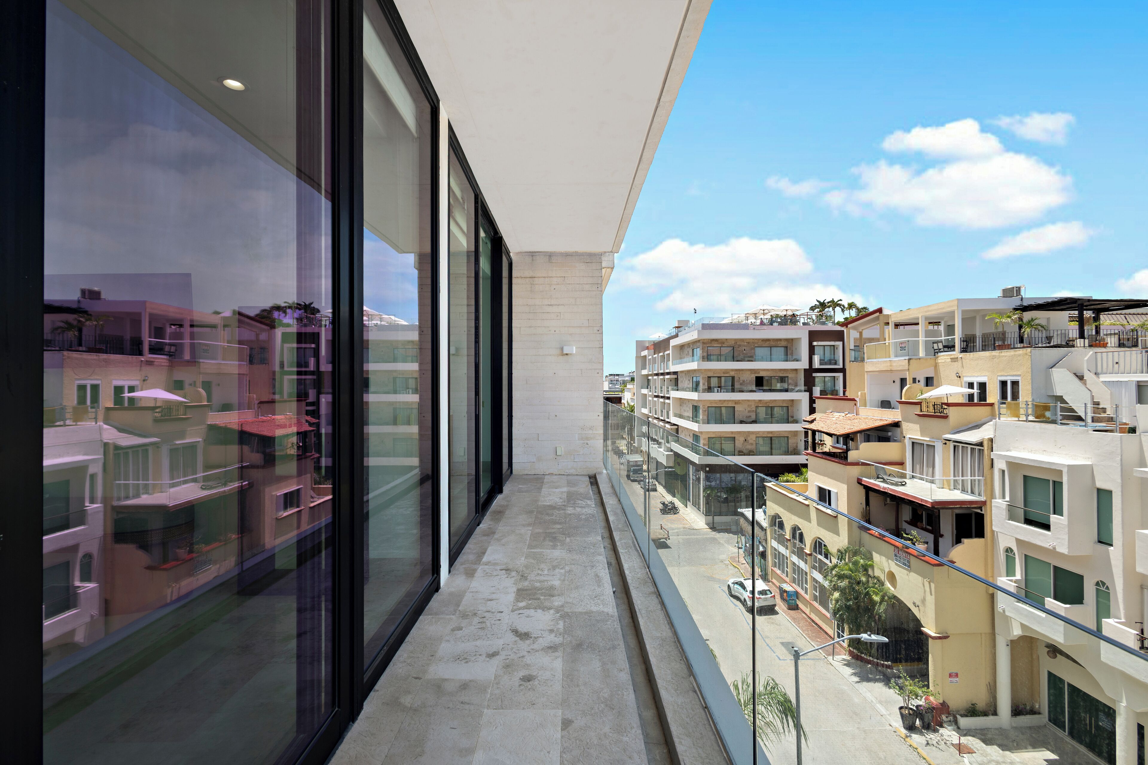 A balcony with a view of neighboring buildings and a clear sky.