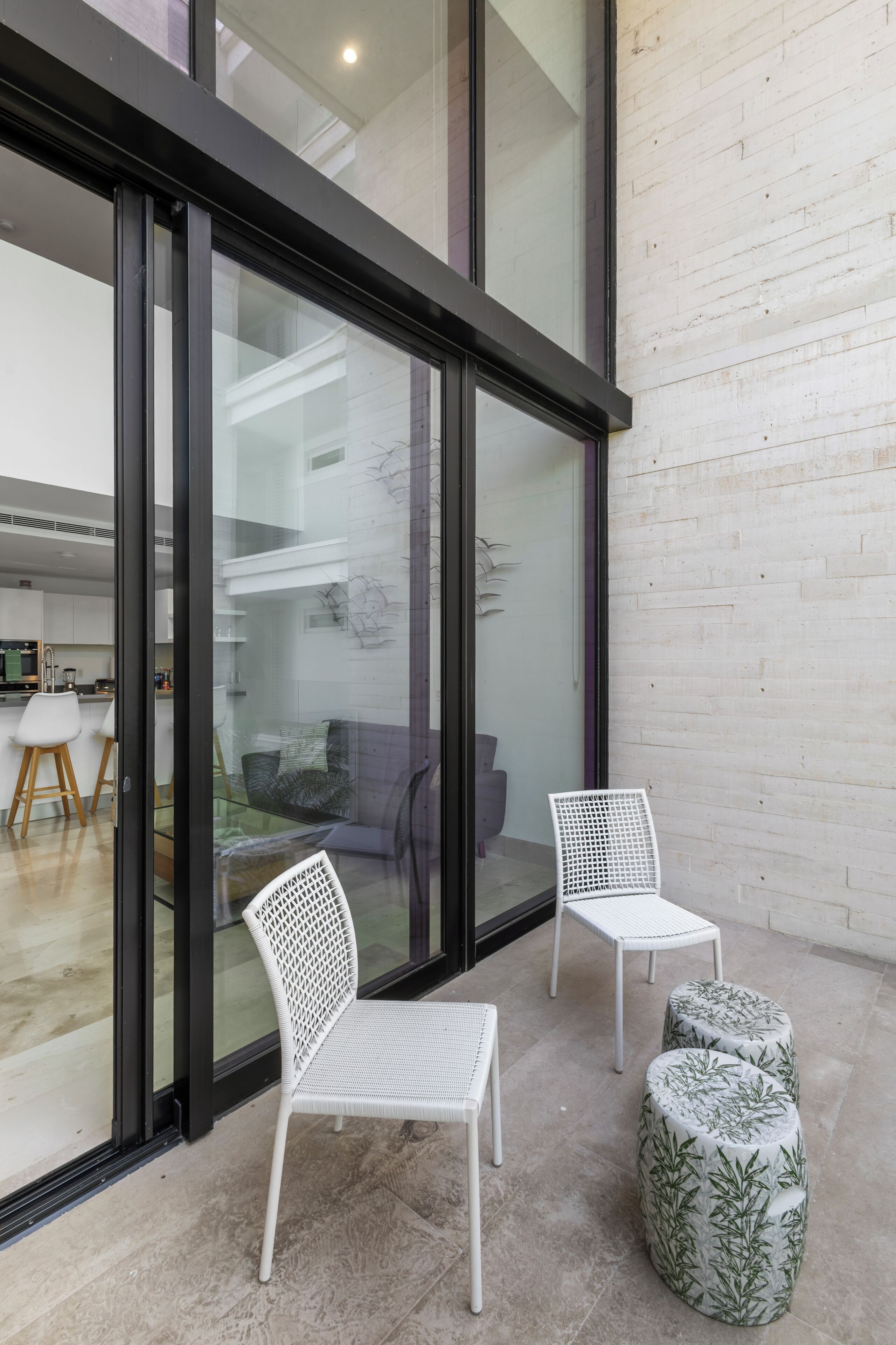 Um interior moderno com parede de vidro, cadeiras brancas e uma pequena mesa.