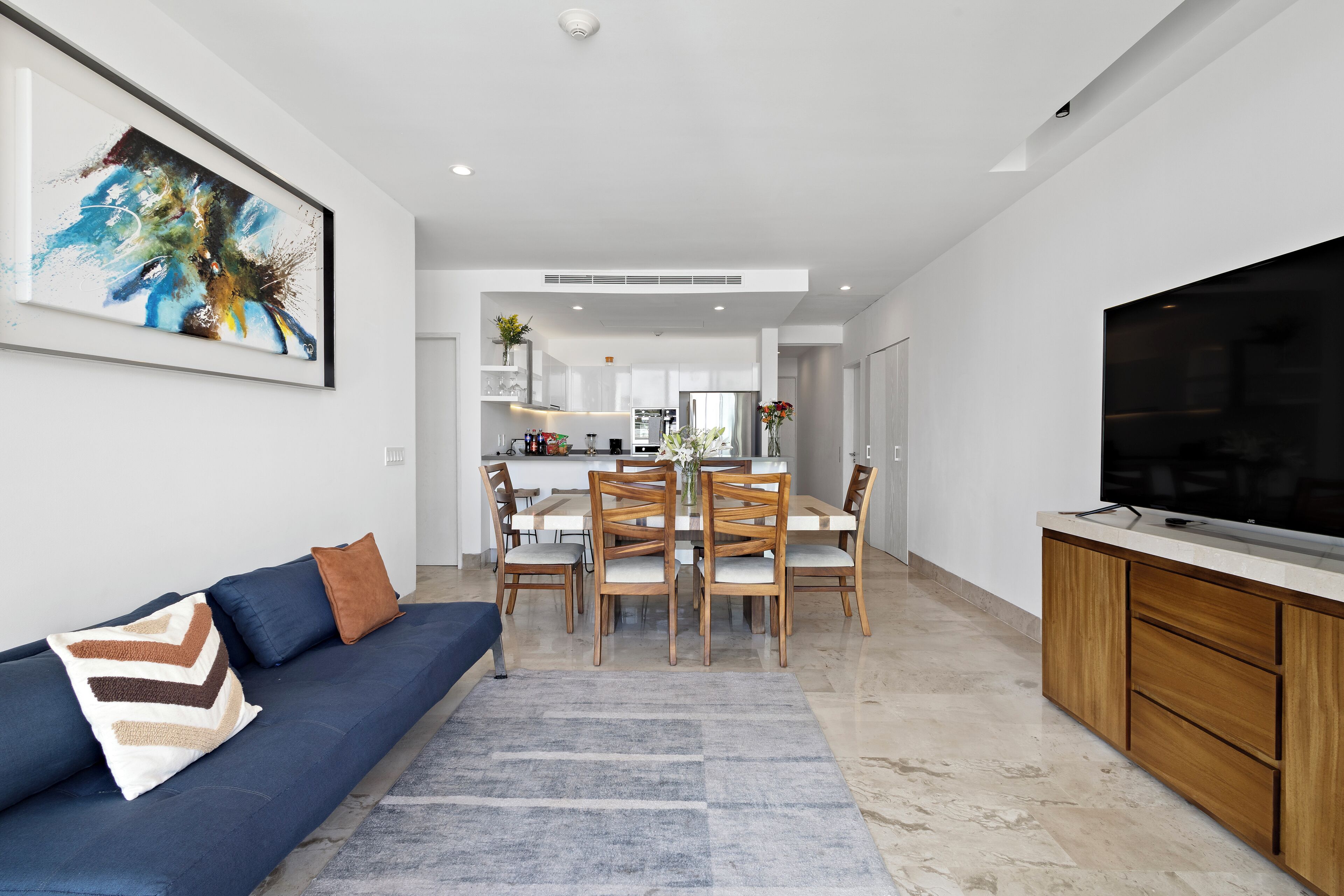 Un salon moderne avec un canapé, un téléviseur et un coin repas.