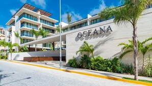 Un hôtel moderne, reconnaissable à son grand panneau « OCEANA », qui se distingue par son architecture à plusieurs étages, ses balcons et un espace paysager agrémenté de plantes tropicales.