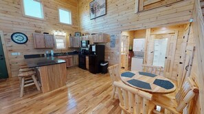 L’intérieur d’un chalet en bois comprend une cuisine, un coin repas et une grande fenêtre.