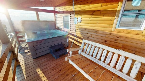 A wooden cabin with a hot tub, a wooden bench, and a window.