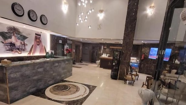 Una moderna hall d'albergo con una reception, un'ampia parete decorativa e un'area salotto con divani e un tavolino da caffè.