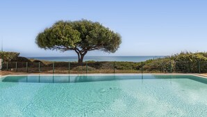 A clear swimming pool with a tree in the background and a view of the sea. - Townhouse w/ Rooftop & Sea View in Benagil (Benagil)