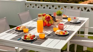 A table set for breakfast with a view of the sea and a sailboat in the distance. - Townhouse w/ Rooftop & Sea View in Benagil (Benagil)