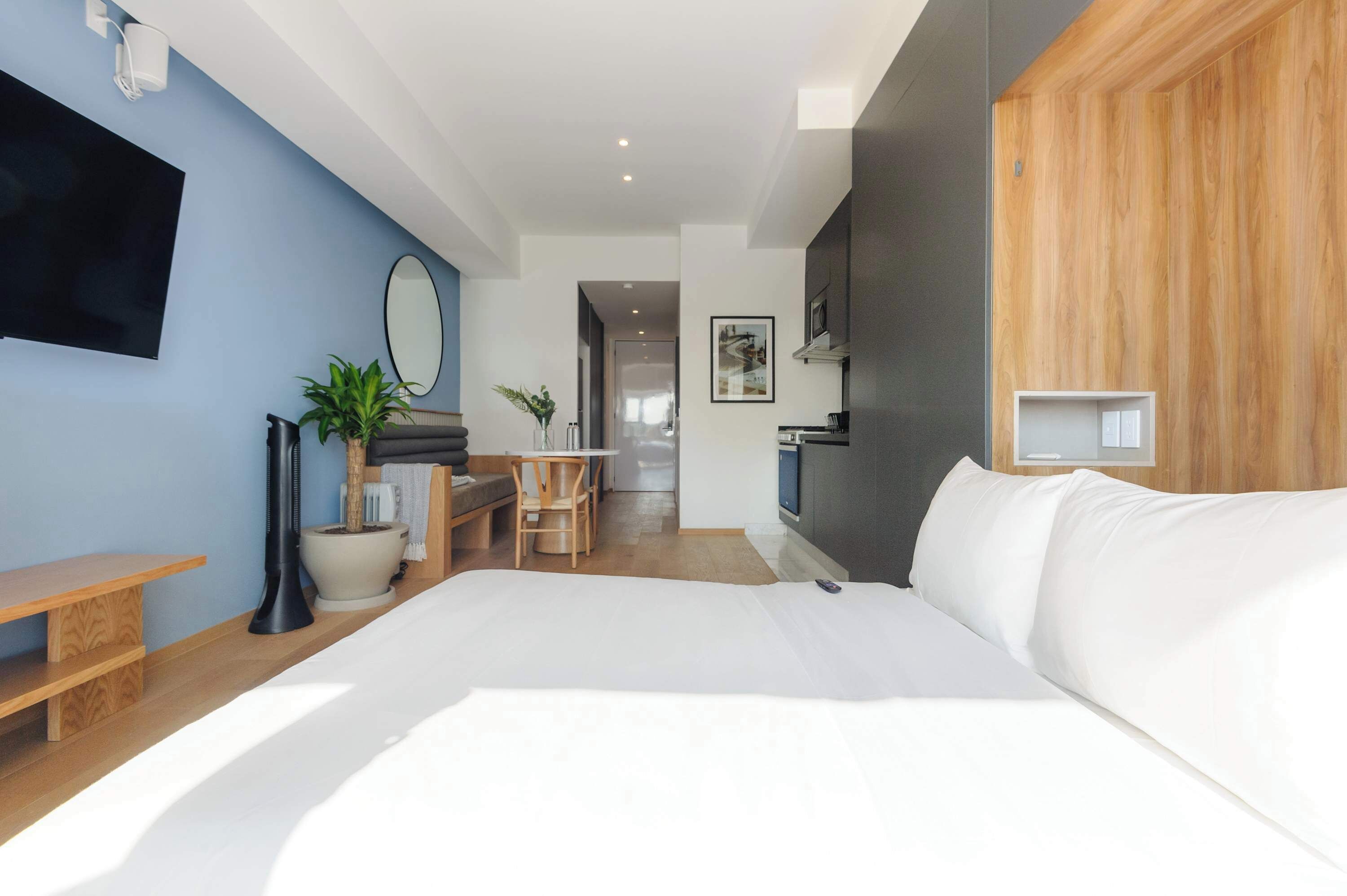 Une chambre d’hôtel moderne dotée d’un grand lit, d’un bureau, d’une chaise, d’une télévision et d’un mur décoratif en bois.