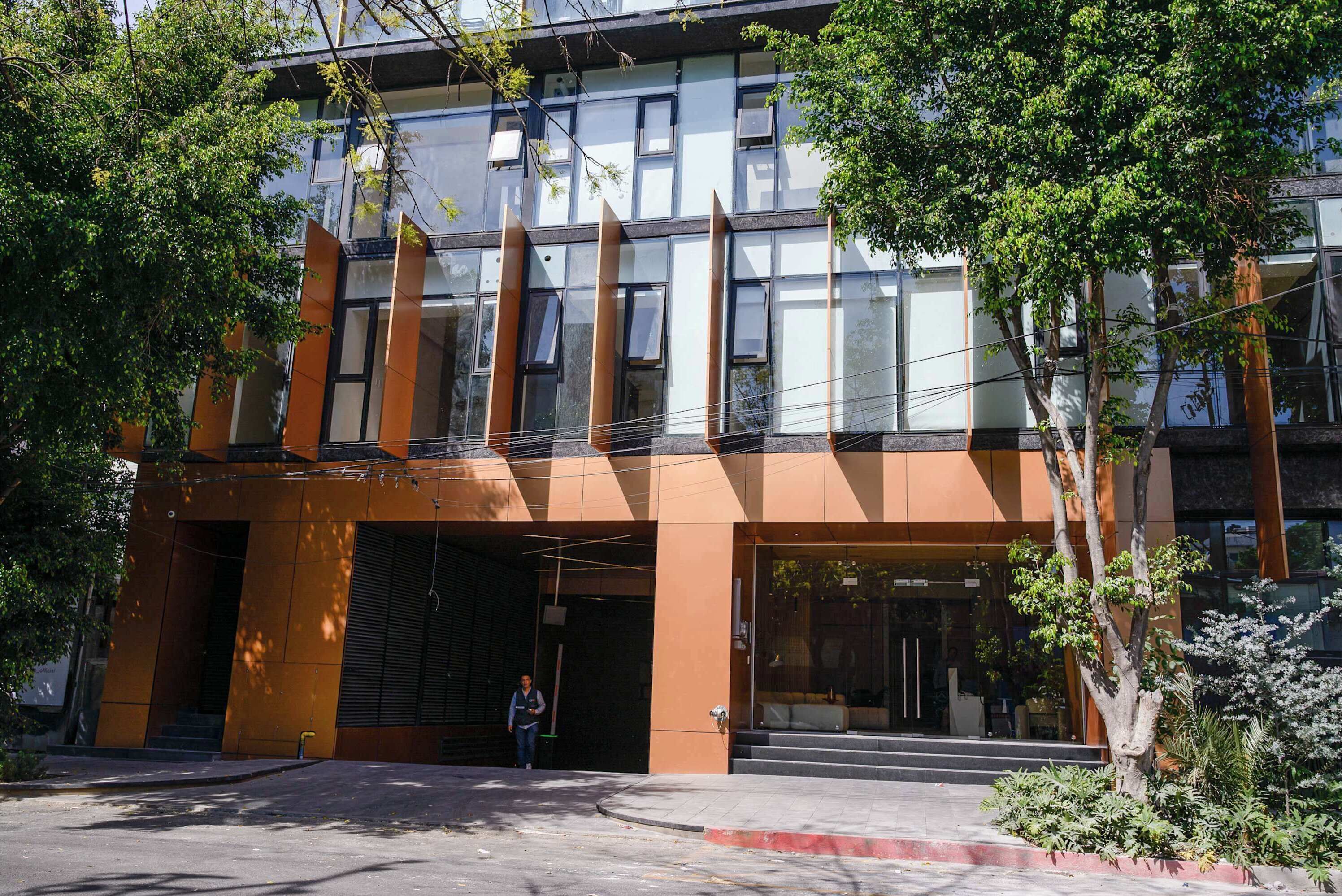 A modern building with a glass facade, large windows, and a brown exterior.