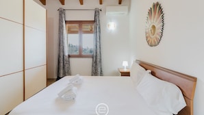 Camera d'albergo con un letto, una finestra con tende, una lampada a parete e un elemento decorativo a parete.
