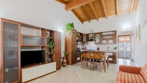 Una cucina moderna con mobili in legno, un'area pranzo con sedie e una TV su un mobile.