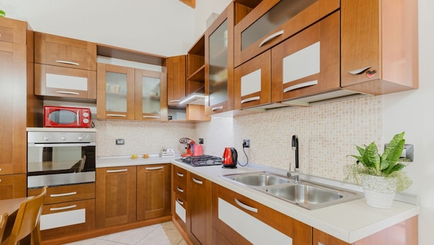 Una cucina moderna con mobili in legno, un forno a microonde rosso, un forno e un lavello.