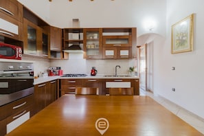 A modern kitchen with wooden cabinets, a stainless steel stove, and a large wooden dining table.