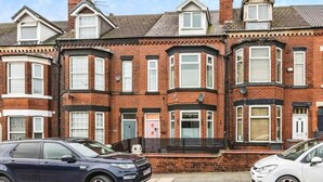 A row of red brick terraced houses with bay windows and a black metal fence in front. - Luxury 5 bed salford home (free parking) (Salford)