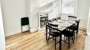 A dining area with a round table, black chairs, and pendant lights. - Luxury 5 bed salford home (free parking) (Salford)