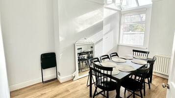 A dining area with a round table, black chairs, and pendant lights.